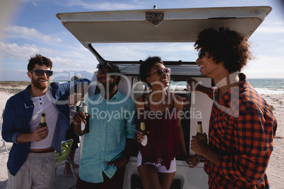 Group of friends enjoying at beach while standing near camper van