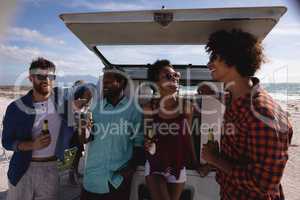 Group of friends enjoying at beach while standing near camper van