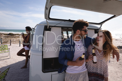 Couple interacting with each other while having beer at beach