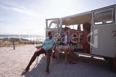 Group of friends enjoying at beach in a camper van