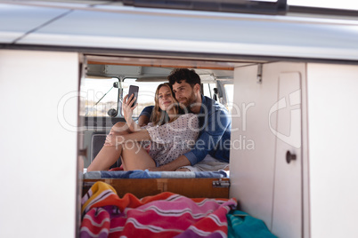 Couple taking a selfie in camper van at beach