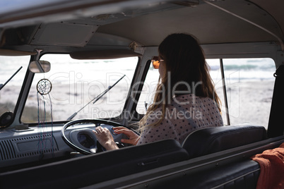 Beautiful woman driving a camper van at beach on a sunny day