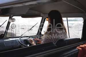 Beautiful woman driving a camper van at beach on a sunny day