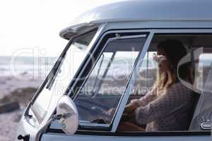 Beautiful woman driving camper van at beach on a sunny day