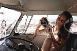 Beautiful woman using digital camera in camper van at beach