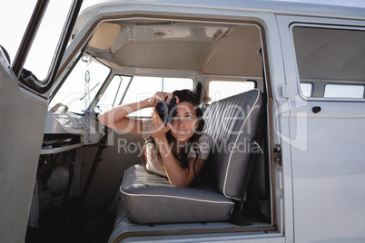 Beautiful woman capturing photo with digital camera in camper van