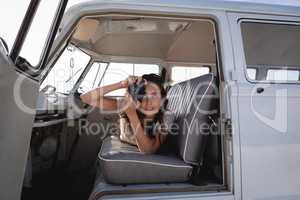 Beautiful woman capturing photo with digital camera in camper van