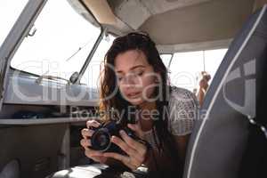 Beautiful woman using digital camera in camper van at beach