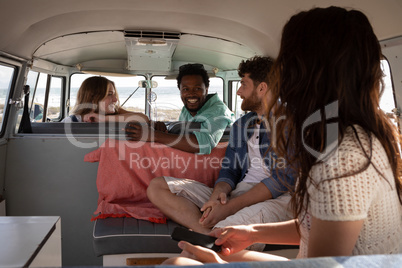 Group of friends interacting with each others in camper van at beach