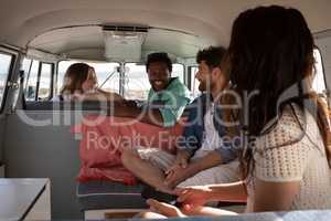 Group of friends interacting with each others in camper van at beach