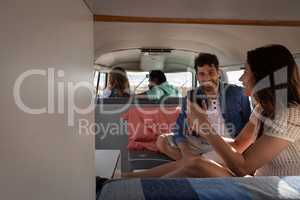 Group of friends interacting with each others in camper van at beach