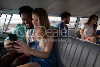 Group of friends interacting with each others in camper van at beach