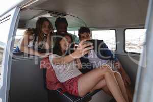 Group of friends taking a selfie in a camper van at beach
