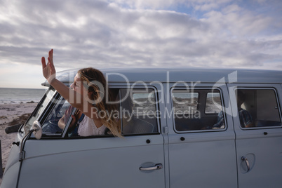 Woman having his head outside the camper van while she is waving out by window