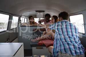 Group of friends giving fist bump in camper van at beach