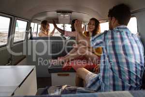 Group of friends giving high five in camper van at beach