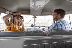 Woman taking photo of a man with digital camera in camper van