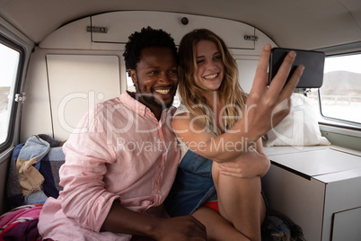 Couple taking a selfie in camper van at beach