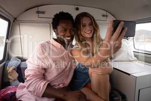 Couple taking a selfie in camper van at beach
