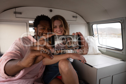 Couple taking selfie in camper van at beach