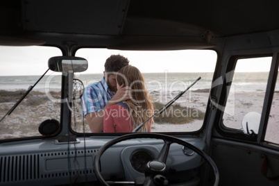 Inside view of a camper van of a Caucasian couple hugging each other against ocean in background