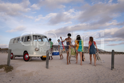 Group of friends come back from beach to join their camper van