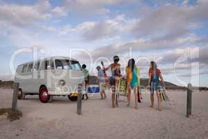 Group of friends come back from beach to join their camper van