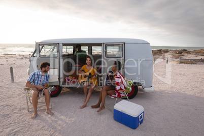 Group of friends enjoying at beach while standing near camper van