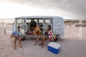 Group of friends enjoying at beach while standing near camper van