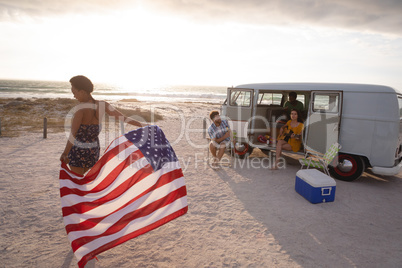 Mixed-race woman holding an American flag against his friends in background