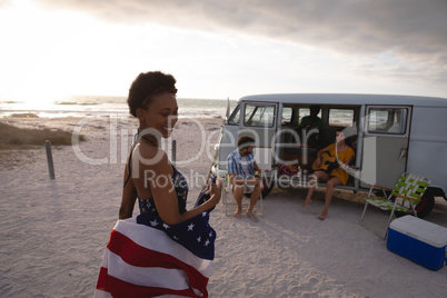 Mixed-race woman holding an American flag against his friends in background