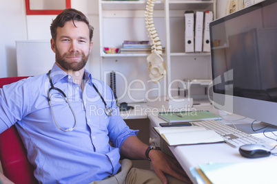 Confident male doctor sitting in clinic