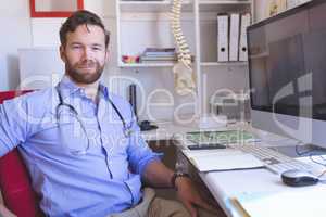 Confident male doctor sitting in clinic