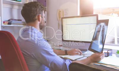 Male doctor checking  x ray report in computer at clinic