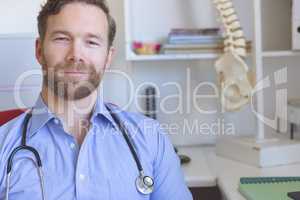 Confident male doctor sitting in clinic
