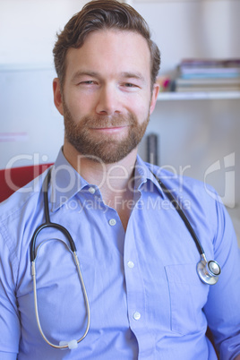 Confident male doctor sitting in clinic