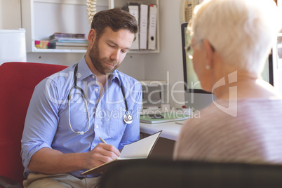 Male doctor and senior woman interacting with each other in clinic
