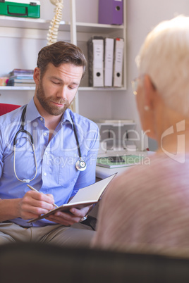 Male doctor and senior woman interacting with each other in clinic