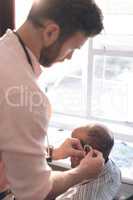 Male doctor applying hearing aid to senior man ear