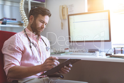 Male doctor checking medical paper in clinic