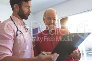 Male doctor showing medical report to a senior patient