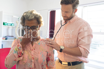 Male doctor examining a senior patient thanks to a stethoscope