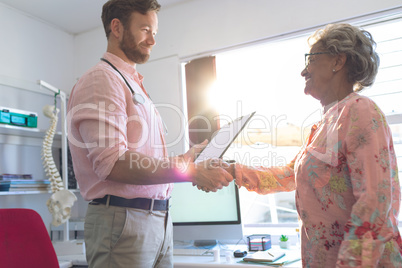 Male doctor interacting with female senior patient in clinic