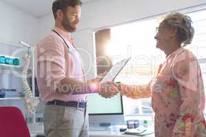 Male doctor interacting with female senior patient in clinic