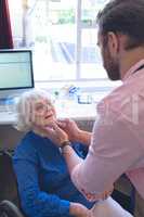 Male doctor checking senior female patient in clinic