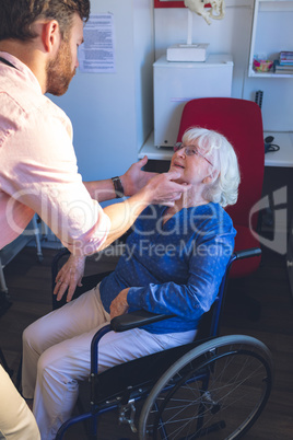 Male doctor checking senior female patient in clinic