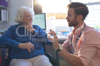 Male doctor talking with senior female patient in clinic