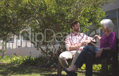 Senior woman talking with doctor outside on nursing home bench