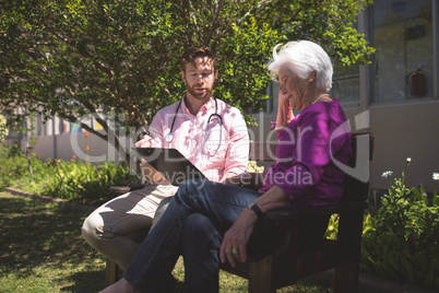 Male doctor showing medical reports to senior woman