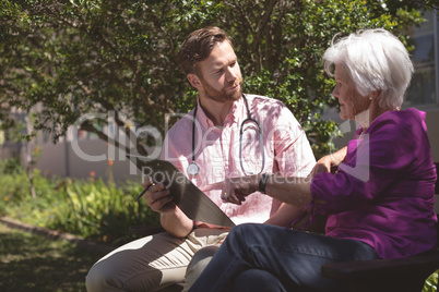 Male doctor showing medical reports to senior woman